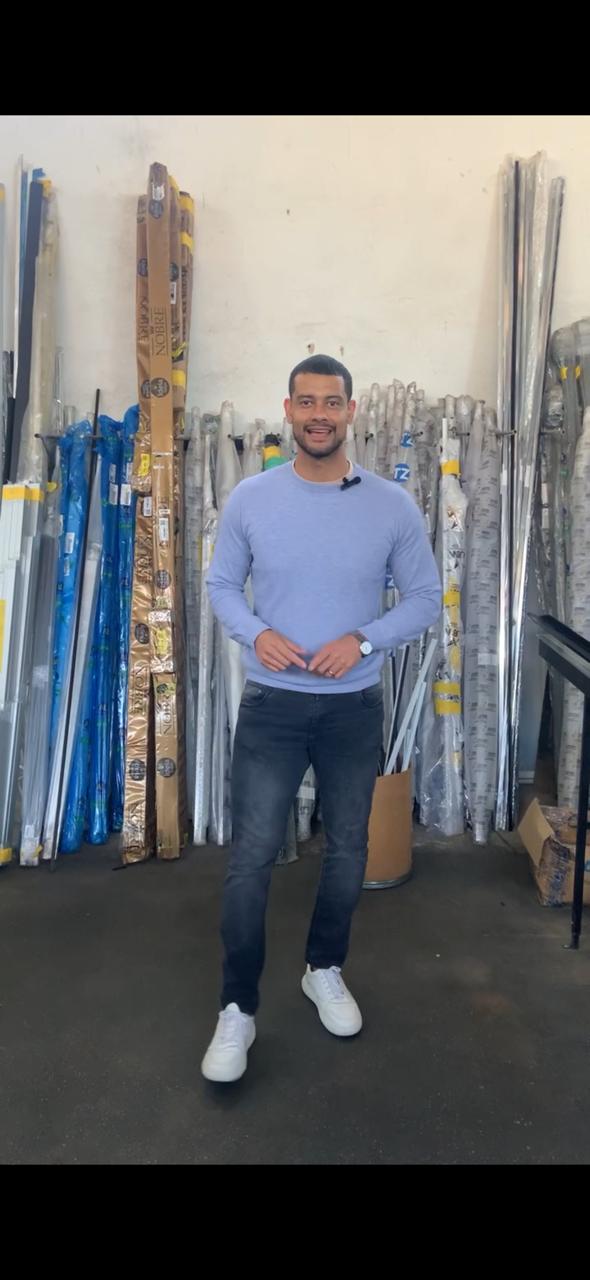 Valdeir na fábrica junto às barras de alumínio